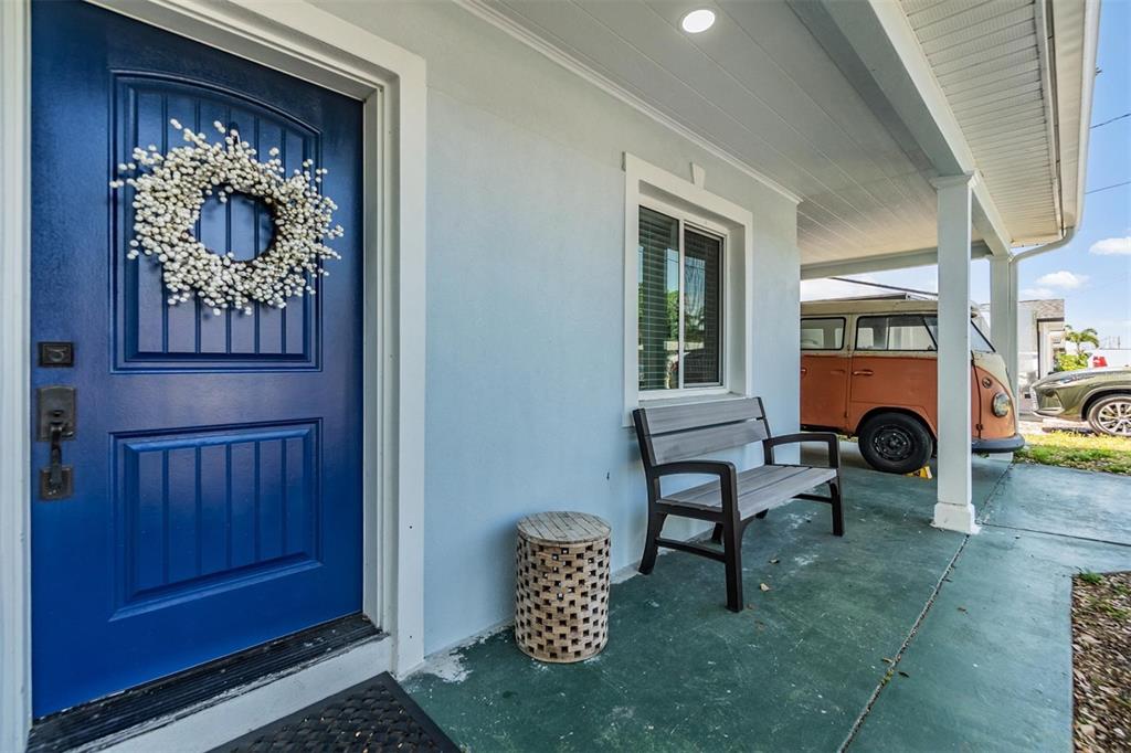 A blue front door with a wreath sits on a porch with a wooden bench — 2808 W LAKE AVENUE, TAMPA, FL