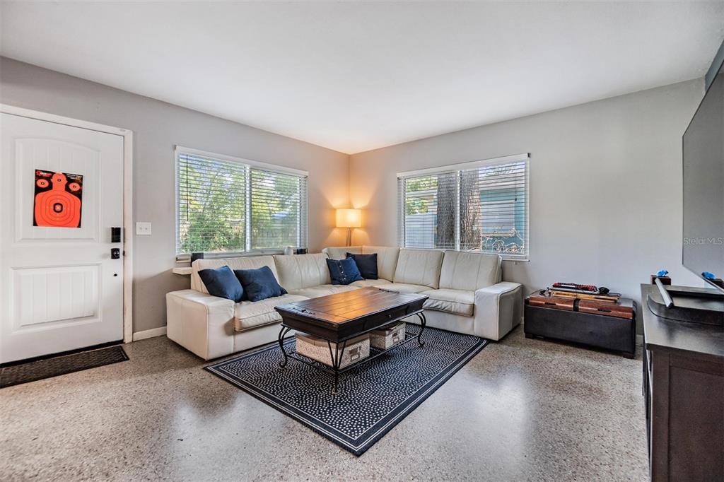 A living room features a white sectional sofa, a wooden coffee table, and concrete floors — 2808 W LAKE AVENUE, TAMPA, FL