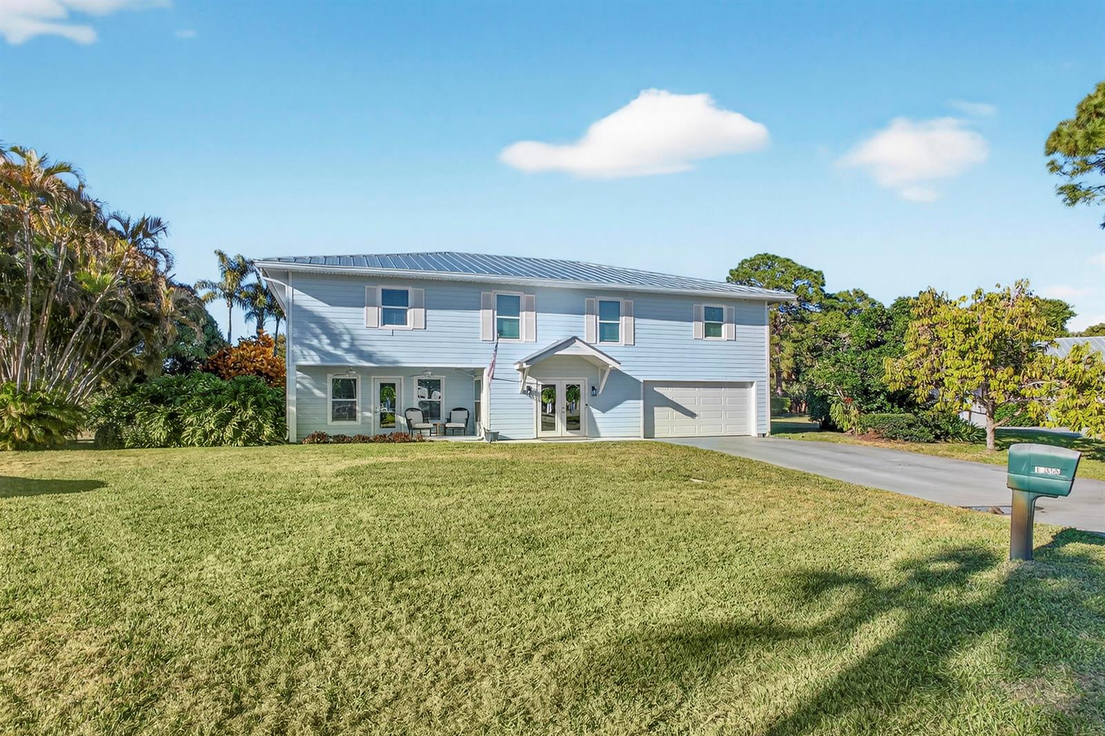 A two-story light blue house with a metal roof and an attached garage — 10355 Seagrape Way, Palm Beach Gardens FL 33418, PALM BEACH GARDENS, FL