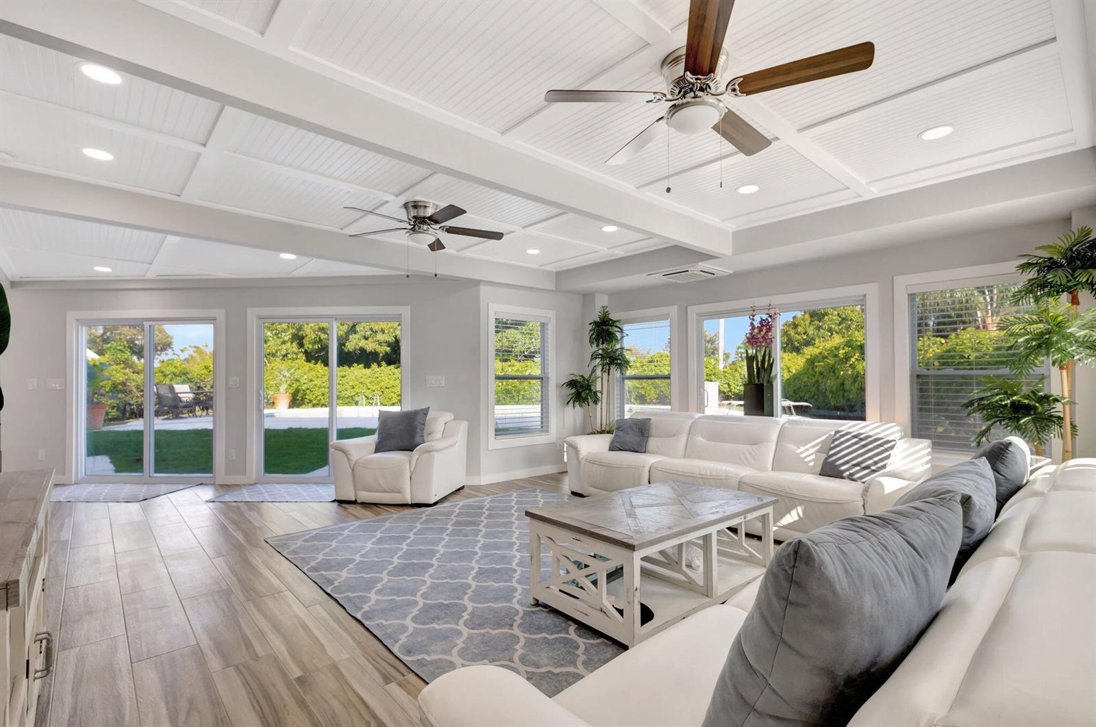 A bright living room features white sofas, a patterned rug, and a coffered ceiling — 10355 Seagrape Way, Palm Beach Gardens FL 33418, PALM BEACH GARDENS, FL