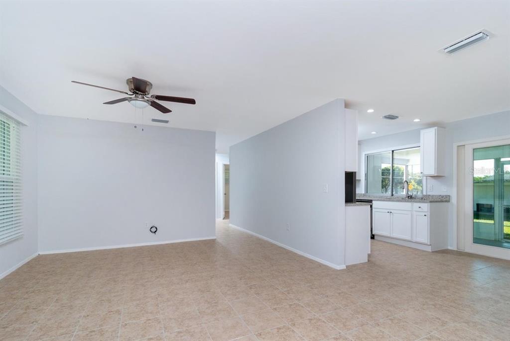 An open-concept living area with light tile flooring, a ceiling fan, and an adjacent kitchen — 533 E CHARLOTTE AVENUE, PUNTA GORDA, FL