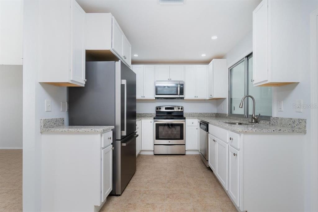 A kitchen with white cabinets, stainless steel appliances, and speckled granite countertops — 533 E CHARLOTTE AVENUE, PUNTA GORDA, FL