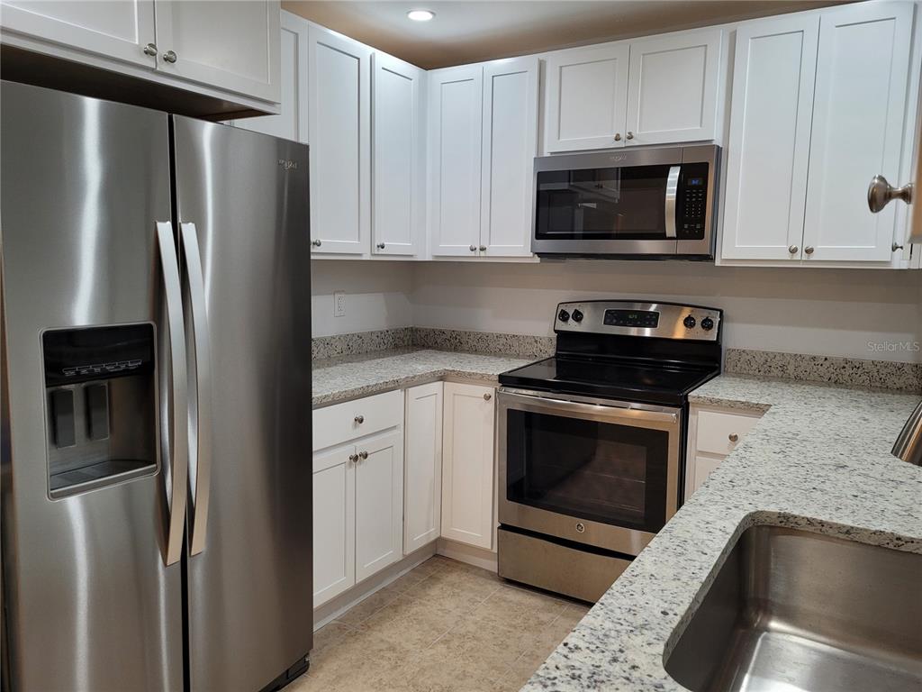 A kitchen features white cabinets, granite countertops, and stainless steel appliances — 533 E CHARLOTTE AVENUE, PUNTA GORDA, FL