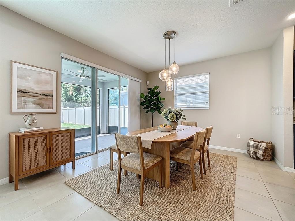 A dining room features a wooden table, chairs, a sideboard, and a large sliding glass door — 13071 BROOKSIDE MOSS DRIVE, RIVERVIEW, FL
