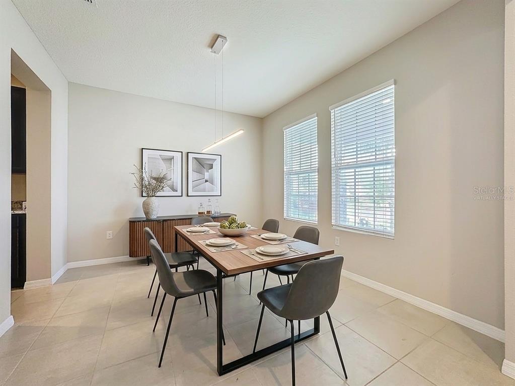 A dining room features a wooden table with six gray chairs and two windows — 13071 BROOKSIDE MOSS DRIVE, RIVERVIEW, FL