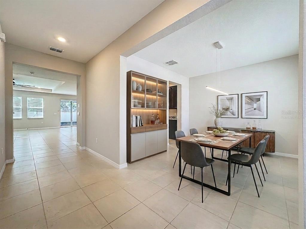 A dining room with a wooden table, grey chairs, and a built-in display cabinet — 13071 BROOKSIDE MOSS DRIVE, RIVERVIEW, FL