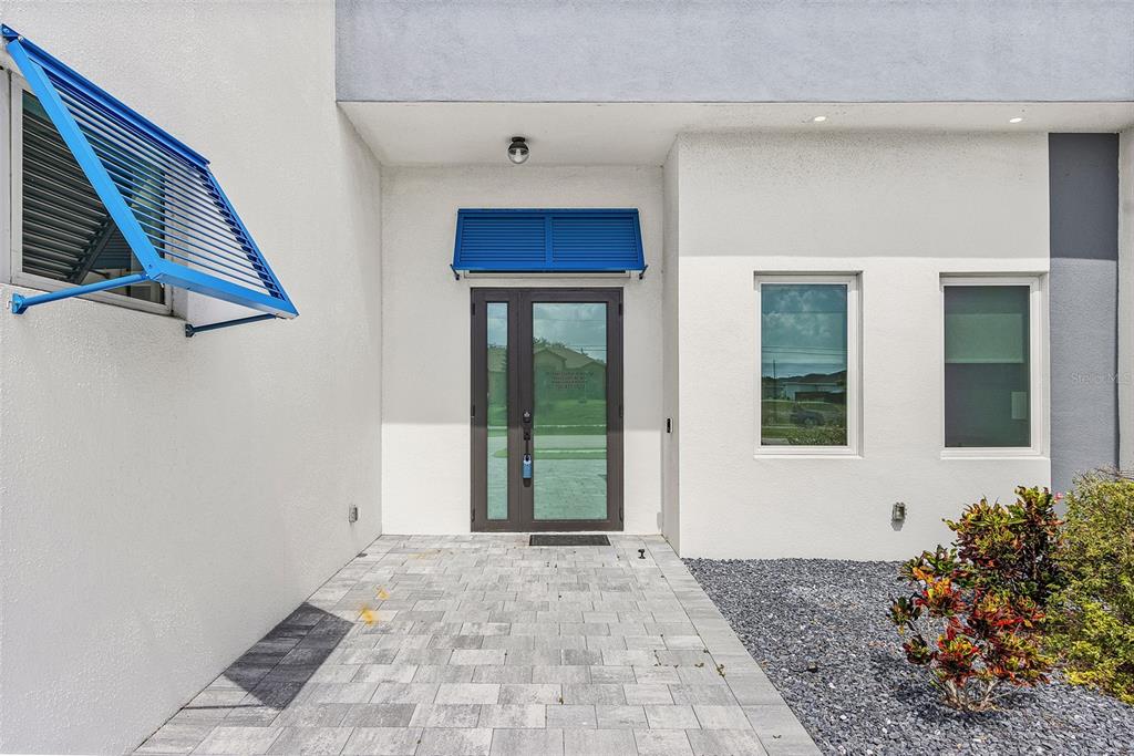 The exterior entrance features a glass front door, blue shutters, and a paved walkway — 300 CHIQUITA BOULEVARD N, CAPE CORAL, FL