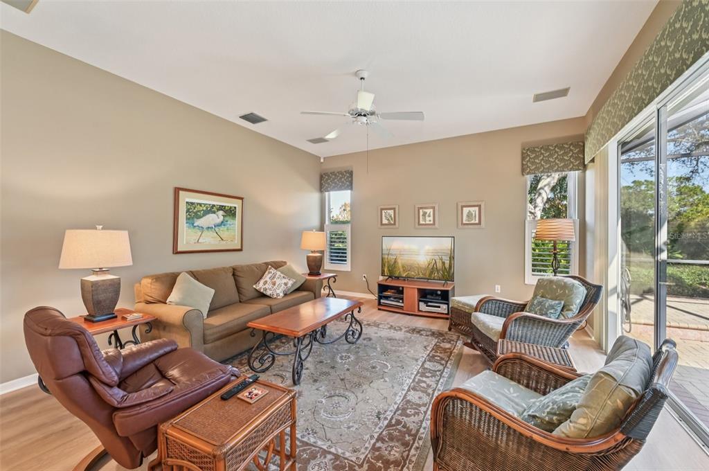 A living room features a brown sofa, leather recliner, wicker chairs, and a sliding glass door — 514 SUMMERFIELD WAY, VENICE, FL