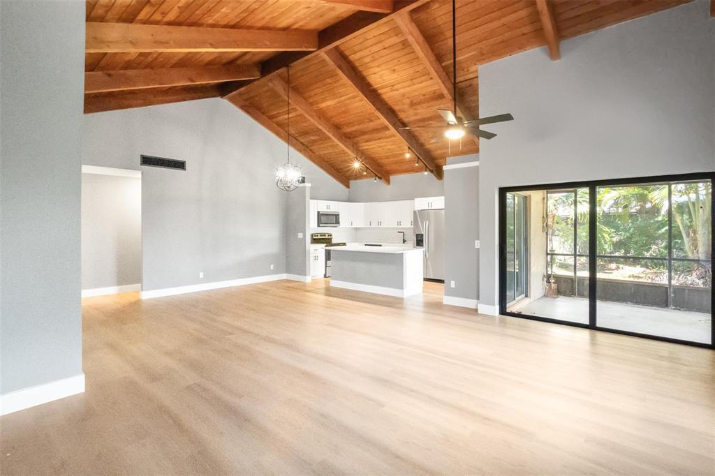 A spacious living area with vaulted wood-beam ceilings, light wood floors, and an open kitchen — 2146 Nova Village Drive, Davie FL 33317, DAVIE, FL