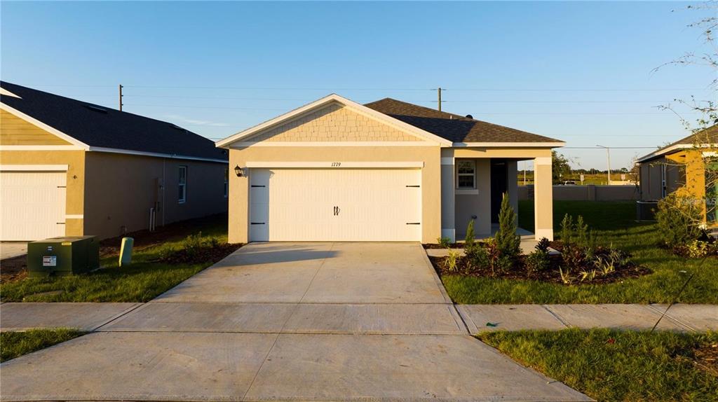A single-story house with a two-car garage and a concrete driveway under a clear sky — 1779 POST OAK DRIVE, DAVENPORT, FL