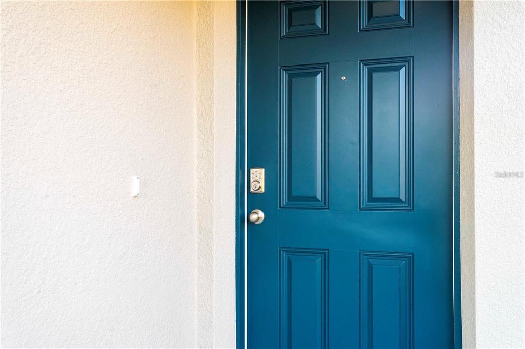 A teal-colored, six-panel front door is set into a light-colored stucco exterior wall — 1779 POST OAK DRIVE, DAVENPORT, FL