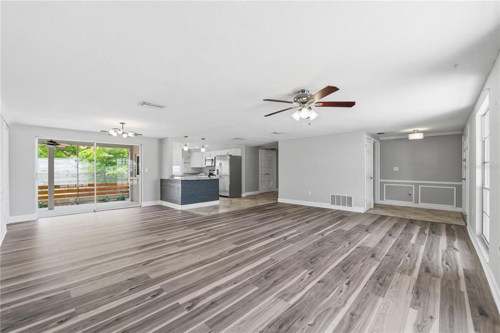 A spacious living area with wood-look flooring, a ceiling fan, and an open-concept kitchen — 4018 CASHMERE DRIVE, NEW PORT RICHEY, FL