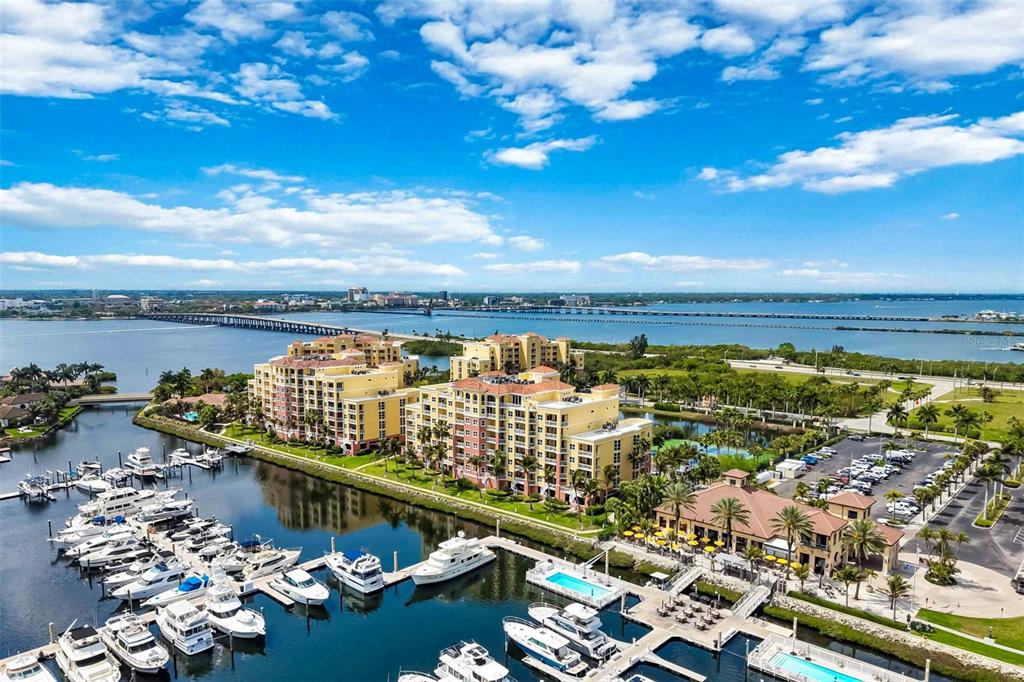 An aerial view shows a waterfront condominium complex with a marina and a long bridge — 606 RIVIERA DUNES WAY UNIT 601, PALMETTO, FL