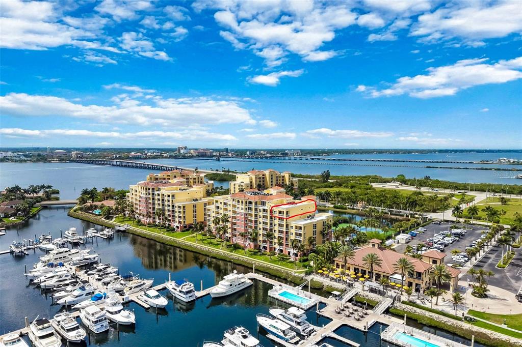 An aerial view shows a waterfront condominium complex with a red-outlined top-floor unit — 606 RIVIERA DUNES WAY UNIT 601, PALMETTO, FL