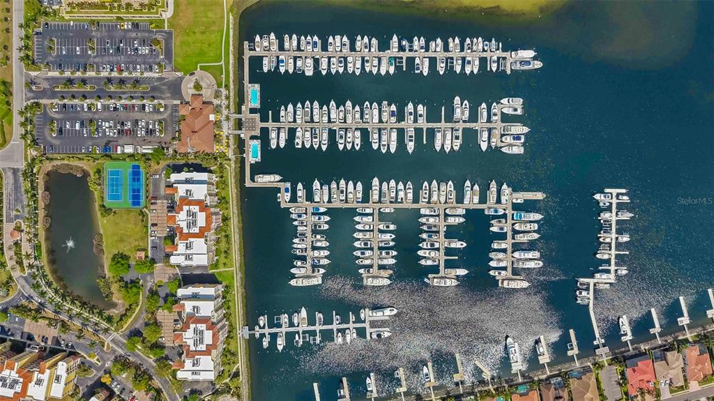 Aerial view of a marina with numerous docked boats, adjacent residential buildings, and parking lots — 606 RIVIERA DUNES WAY UNIT 601, PALMETTO, FL