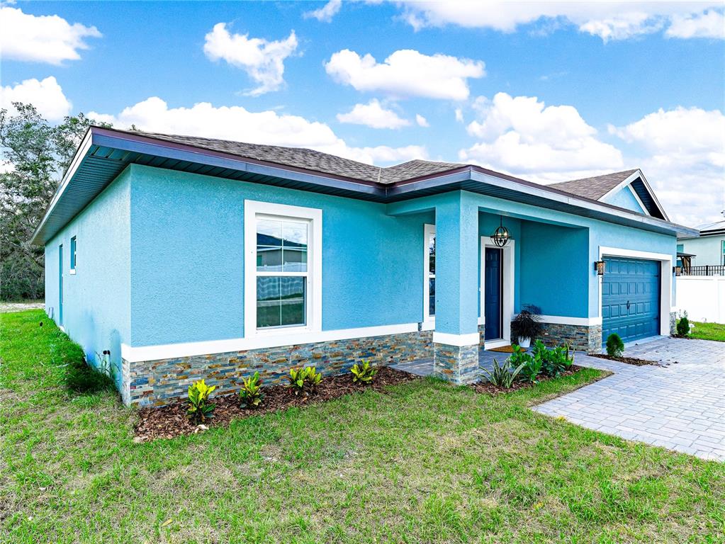 A bright blue single-story house features a stone veneer base and a paved driveway — 47 ORCHID COURT, POINCIANA, FL