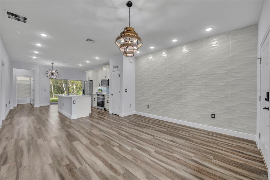 An open-concept dining area features wood-look flooring and a textured white accent wall — 47 ORCHID COURT, POINCIANA, FL
