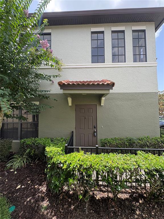 A two-story building exterior features a brown front door, a tiled awning, and hedges — 6133 APOLLOS CORNER WAY, ORLANDO, FL