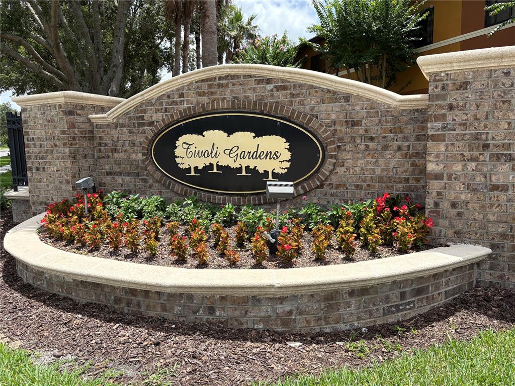 A brick monument sign for Tivoli Gardens sits behind a landscaped flower bed — 6133 APOLLOS CORNER WAY, ORLANDO, FL