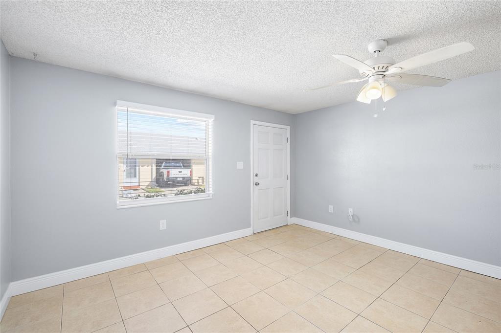 An empty room with light gray walls, tile flooring, a ceiling fan, and a window — 4930 HAZNER STREET, NEW PORT RICHEY, FL