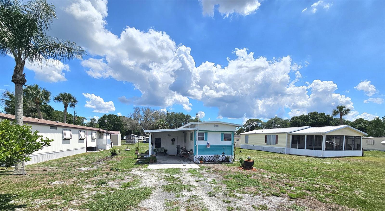 A blue and white mobile home with a carport sits on a grassy lot — 17408 Broadwing Lane, Okeechobee FL 34974, OKEECHOBEE, FL