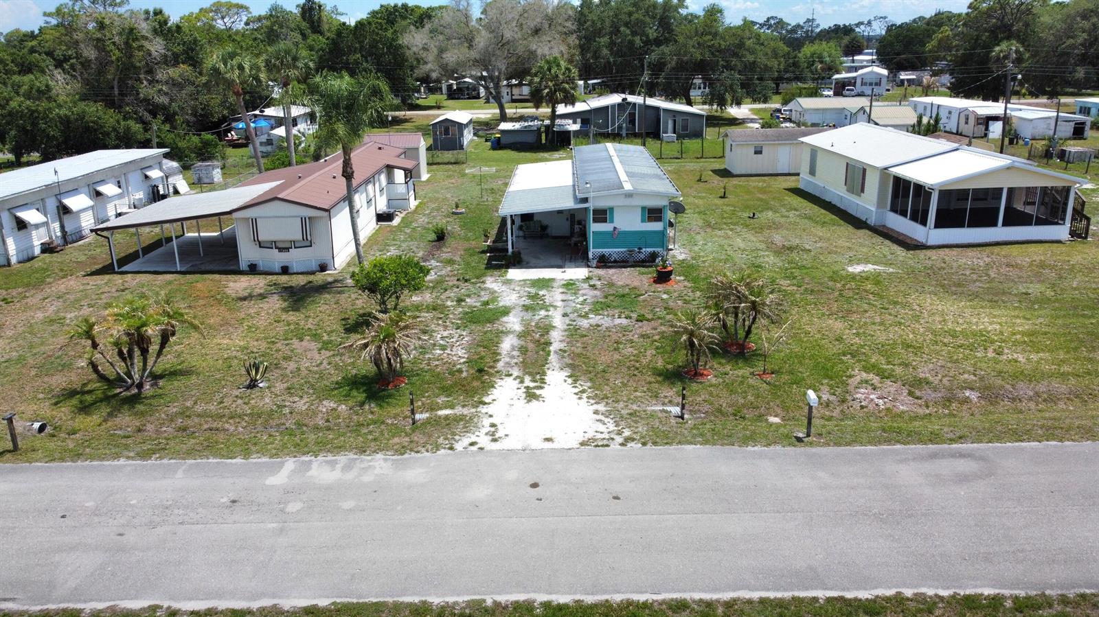 An aerial view shows three mobile homes with carports and driveways along a paved road — 17408 Broadwing Lane, Okeechobee FL 34974, OKEECHOBEE, FL