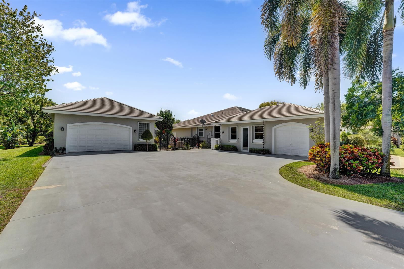 A concrete driveway leads to two separate garage buildings with tiled roofs and palm trees — 5970 SW 55th Street, Davie FL 33314, DAVIE, FL