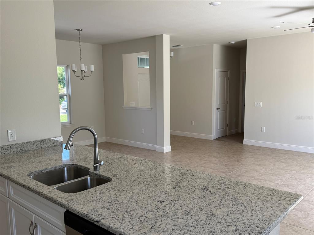 A kitchen island with a granite countertop and stainless steel sink overlooks an open living area — 3462 SERNICE STREET, NORTH PORT, FL