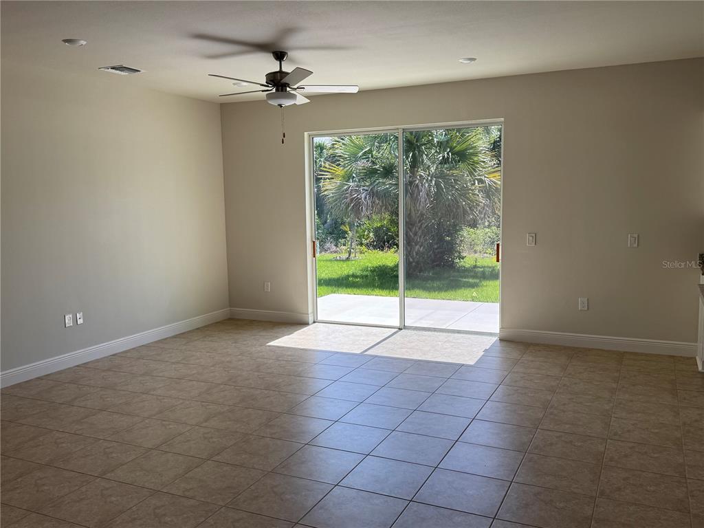 A living room with tile flooring, a ceiling fan, and sliding glass doors to a yard — 3462 SERNICE STREET, NORTH PORT, FL
