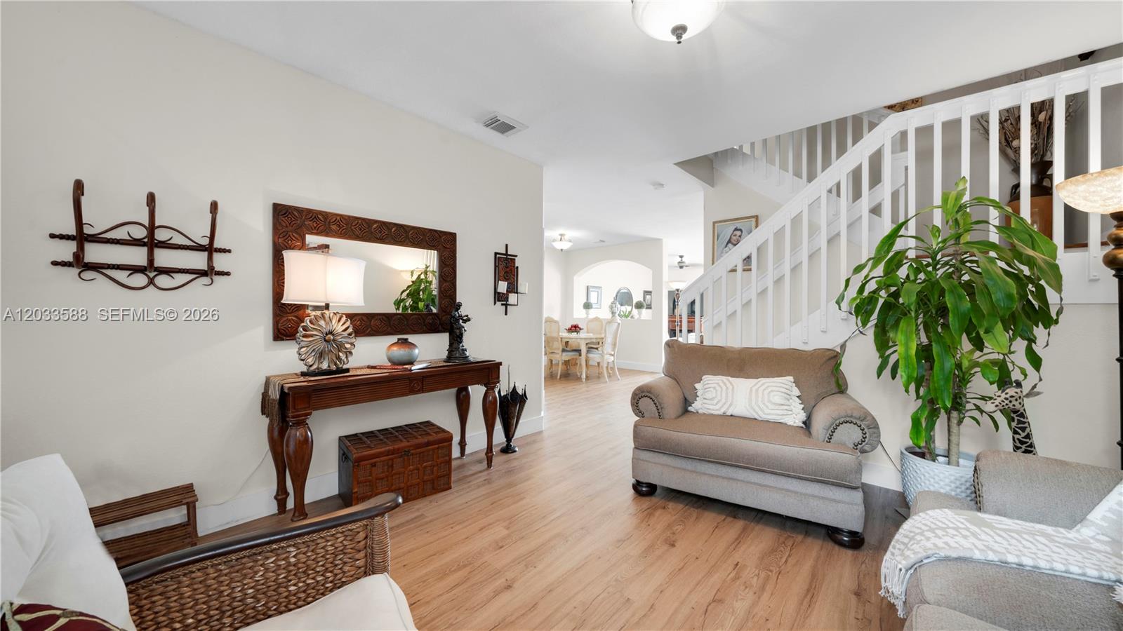 A bright entryway features wood-look flooring, a staircase with white railings, and a console table — 16590 SW 70th St, Miami FL 33193, MIAMI, FL