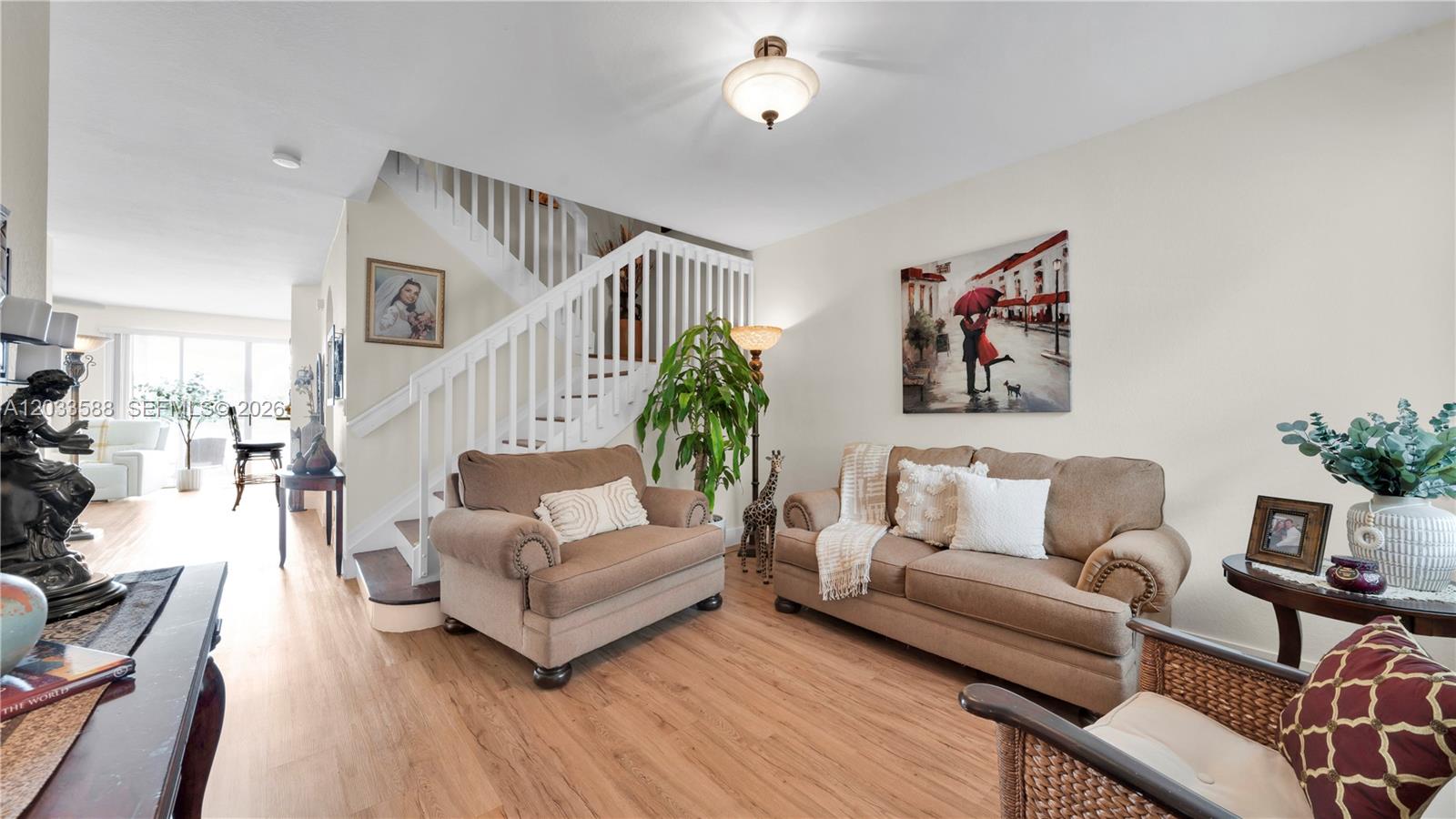 A living room features a staircase, tan sofas, wood-look flooring, and a wall art piece — 16590 SW 70th St, Miami FL 33193, MIAMI, FL
