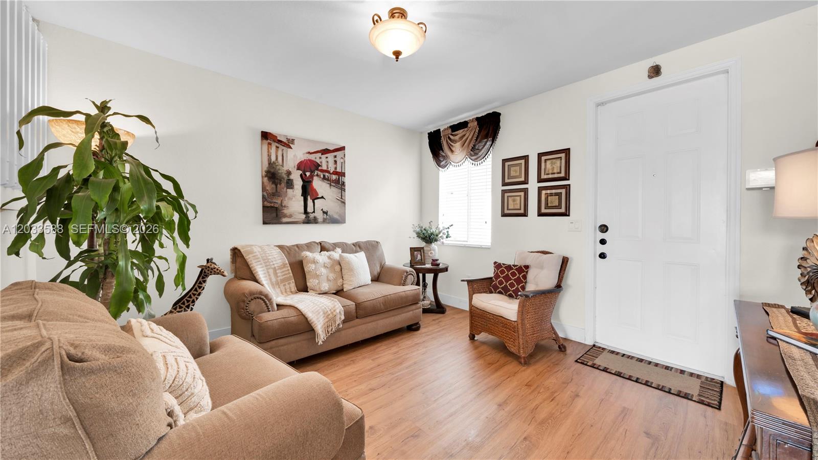 A living room features light walls, wood-look flooring, a sofa, an armchair, and a front door — 16590 SW 70th St, Miami FL 33193, MIAMI, FL
