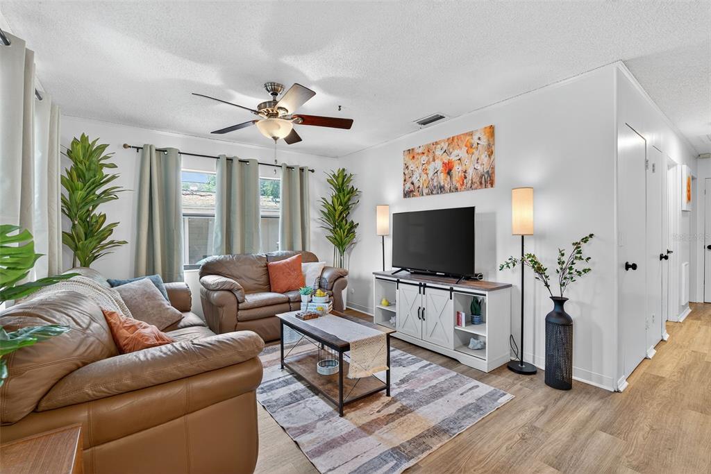 A living room features leather sofas, a television on a white console, and wood flooring — 7009 S FITZGERALD STREET, TAMPA, FL