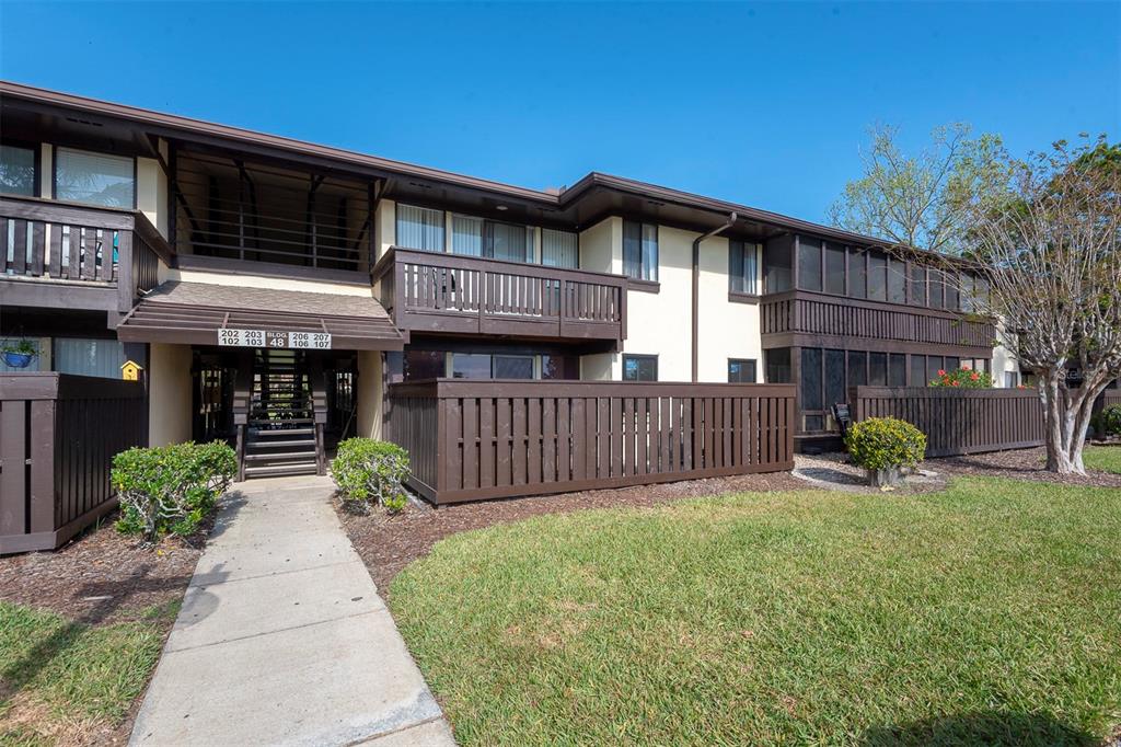 A two-story apartment building with brown wooden balconies and a concrete walkway — 48 CLUB HOUSE DRIVE UNIT 106, PALM COAST, FL
