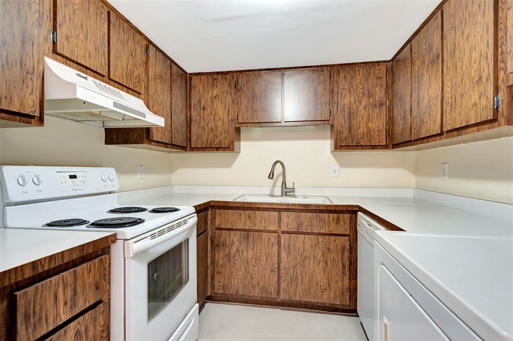 A kitchen features wood-grain cabinets, white appliances, and white countertops — 48 CLUB HOUSE DRIVE UNIT 106, PALM COAST, FL