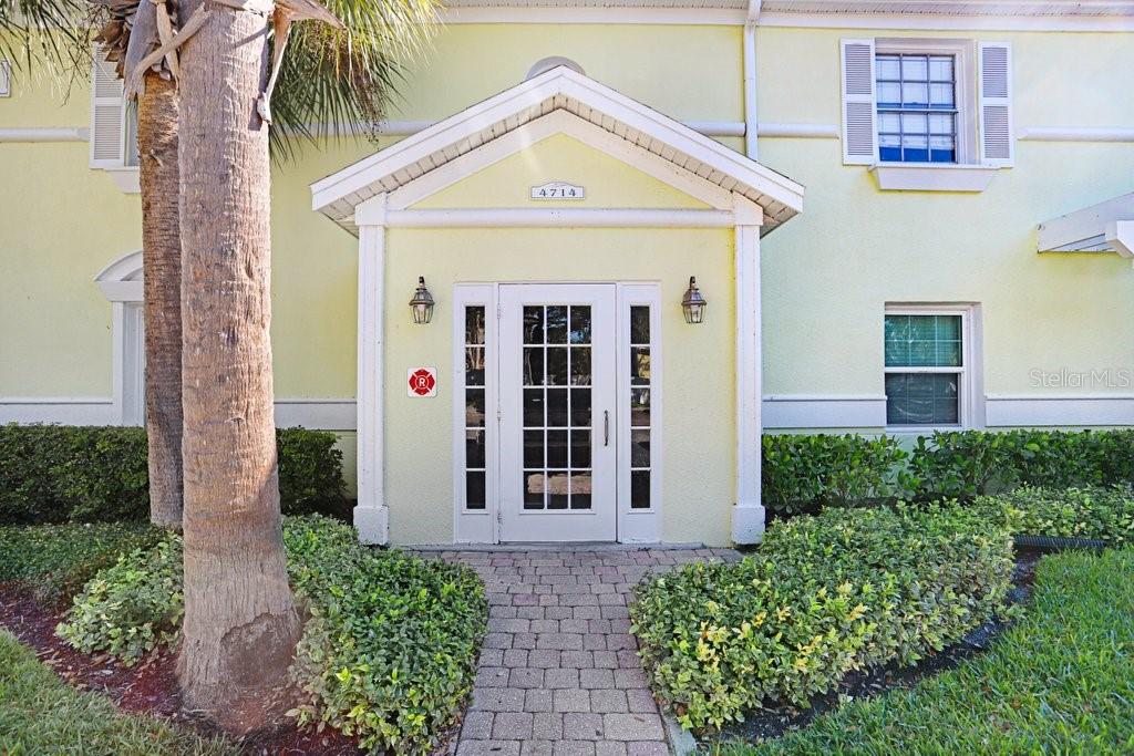A paved walkway leads to the white-framed glass front door of a yellow building — 4714 COBIA DRIVE SE UNIT C, ST PETERSBURG, FL