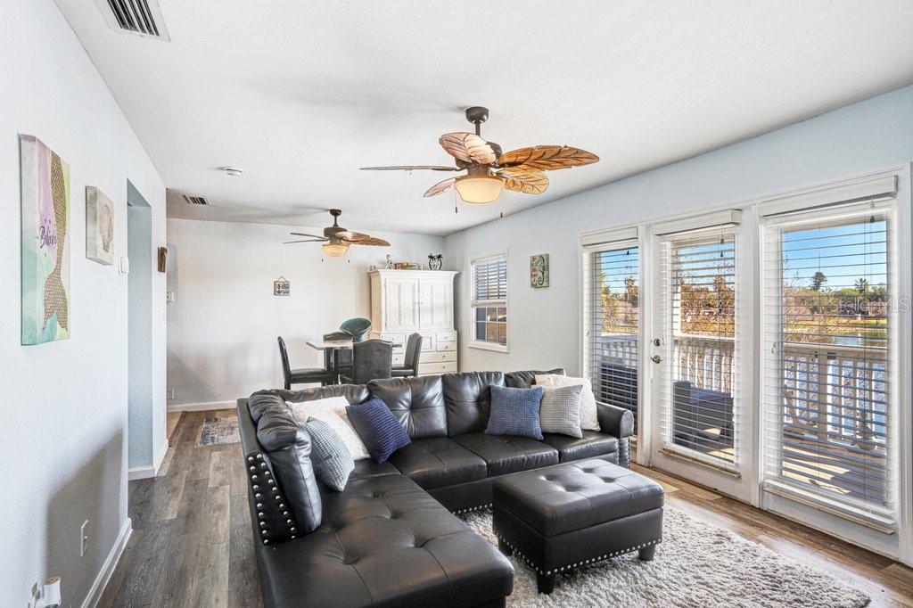 A living room with a black sectional sofa, a matching ottoman, and sliding glass doors — 4714 COBIA DRIVE SE UNIT C, ST PETERSBURG, FL