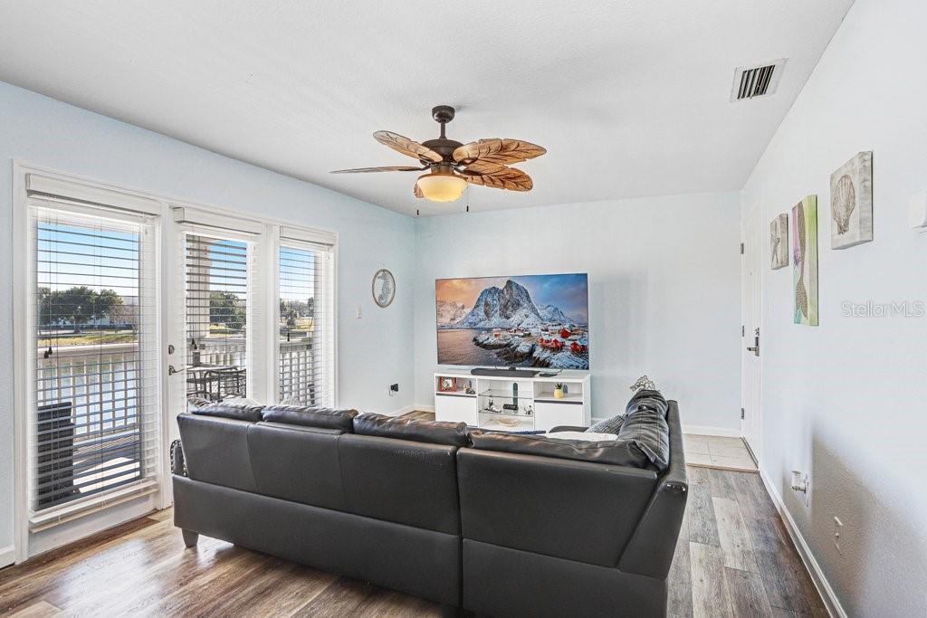 A living room features a dark leather sectional, a television, and a ceiling fan — 4714 COBIA DRIVE SE UNIT C, ST PETERSBURG, FL