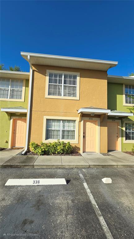 The exterior of a two-story tan townhouse building features light-colored doors and a parking space — 336 CERVANTES DRIVE UNIT 336, KISSIMMEE, FL