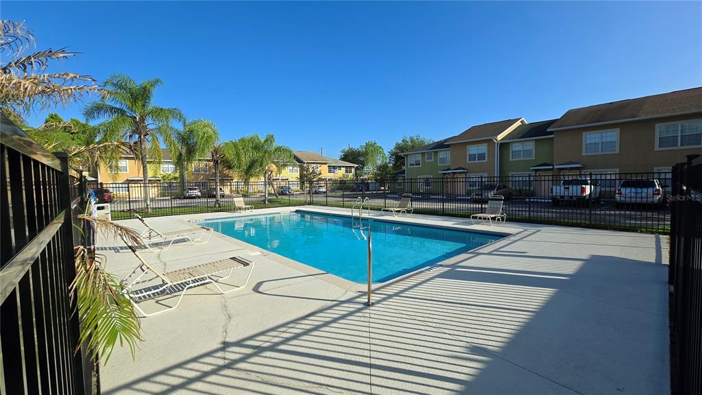 A swimming pool with lounge chairs sits in front of multi-story apartment buildings — 336 CERVANTES DRIVE UNIT 336, KISSIMMEE, FL