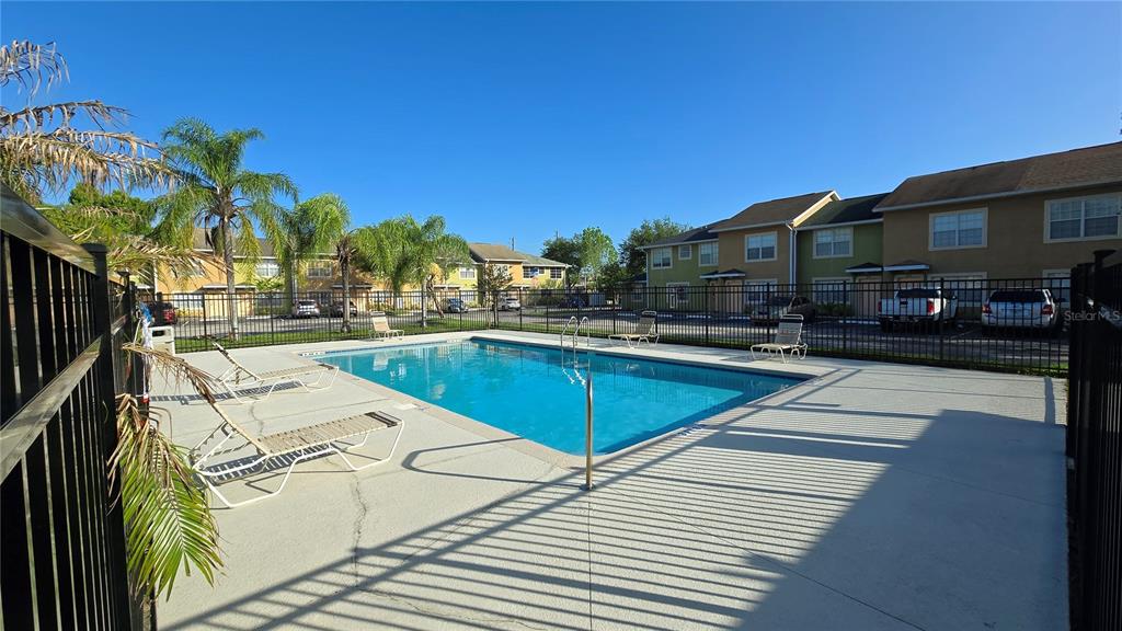 A rectangular swimming pool with lounge chairs sits in front of multi-story apartment buildings — 336 CERVANTES DRIVE UNIT 336, KISSIMMEE, FL