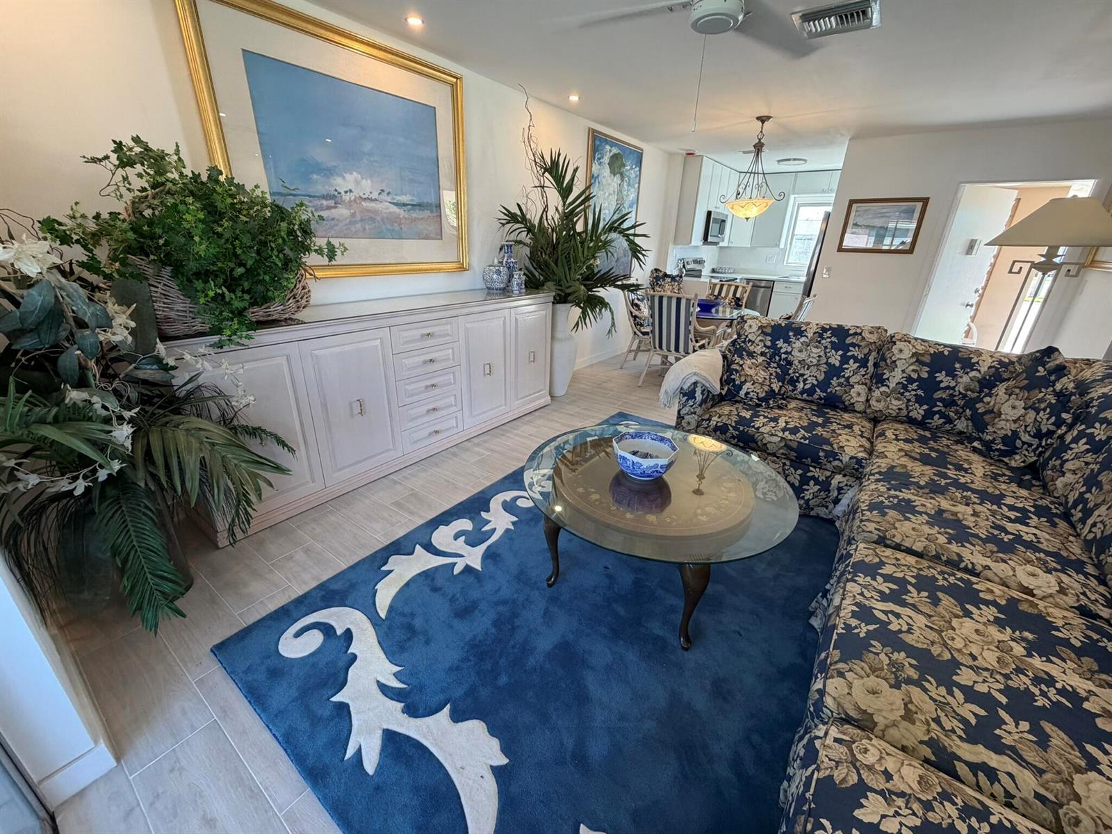 A living room features a blue floral sofa, a glass coffee table, and a blue rug — 2747 E Dudley Dr Drive E # D, West Palm Beach FL 33415, WEST PALM BEACH, FL