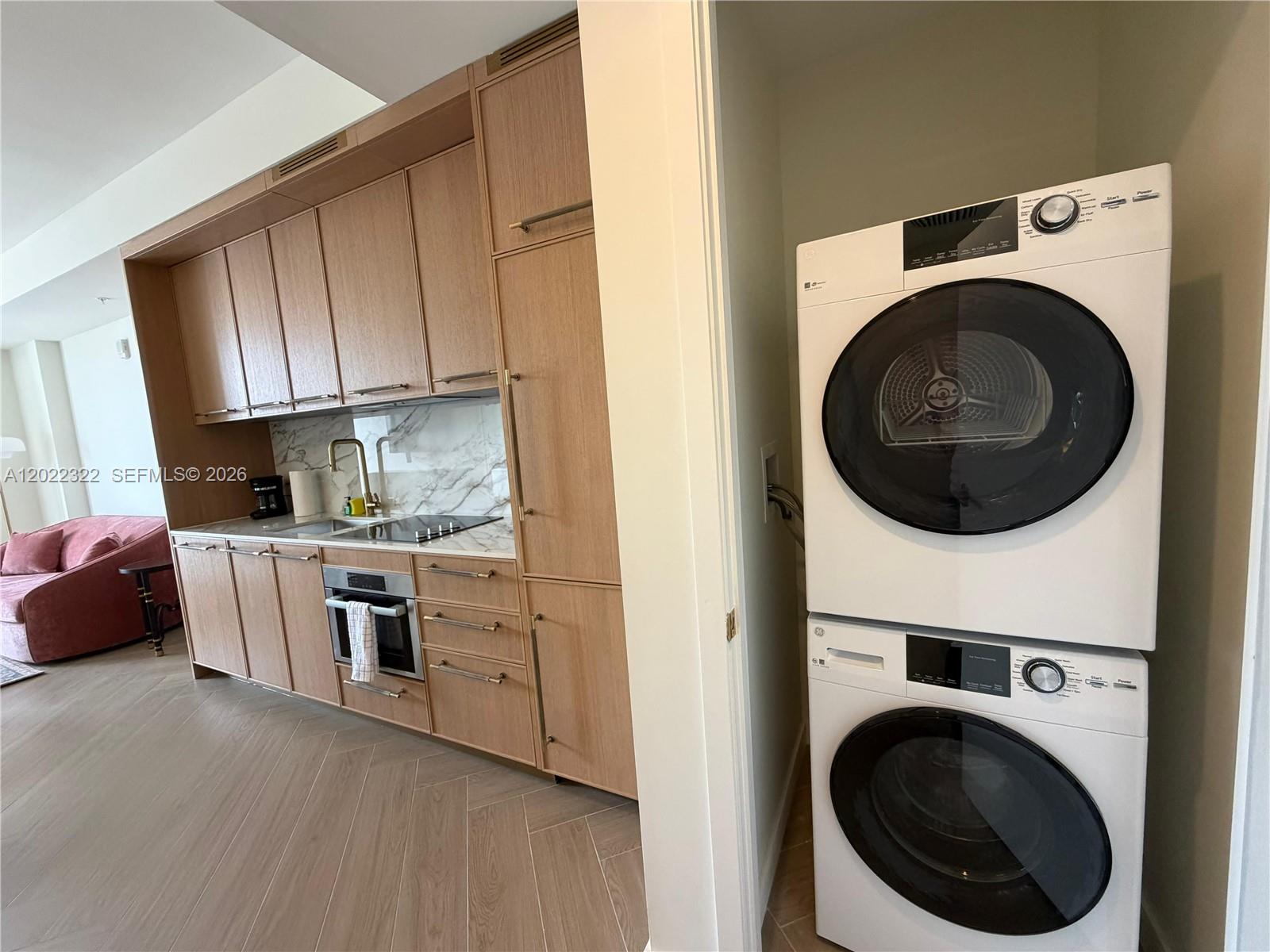 A modern kitchen with light wood cabinetry and a stacked washer-dryer unit nearby — 2700 NW 2nd Ave # 305, Miami FL 33127, MIAMI, FL