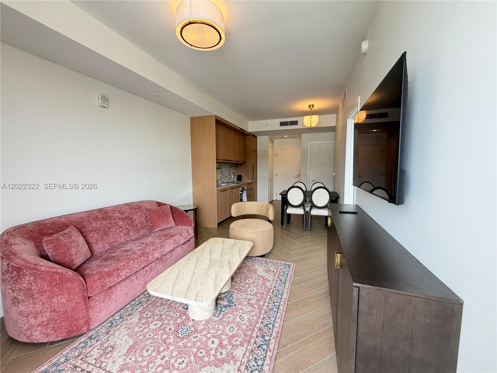 A living room features a pink velvet sofa, a stone coffee table, and a kitchenette — 2700 NW 2nd Ave # 305, Miami FL 33127, MIAMI, FL