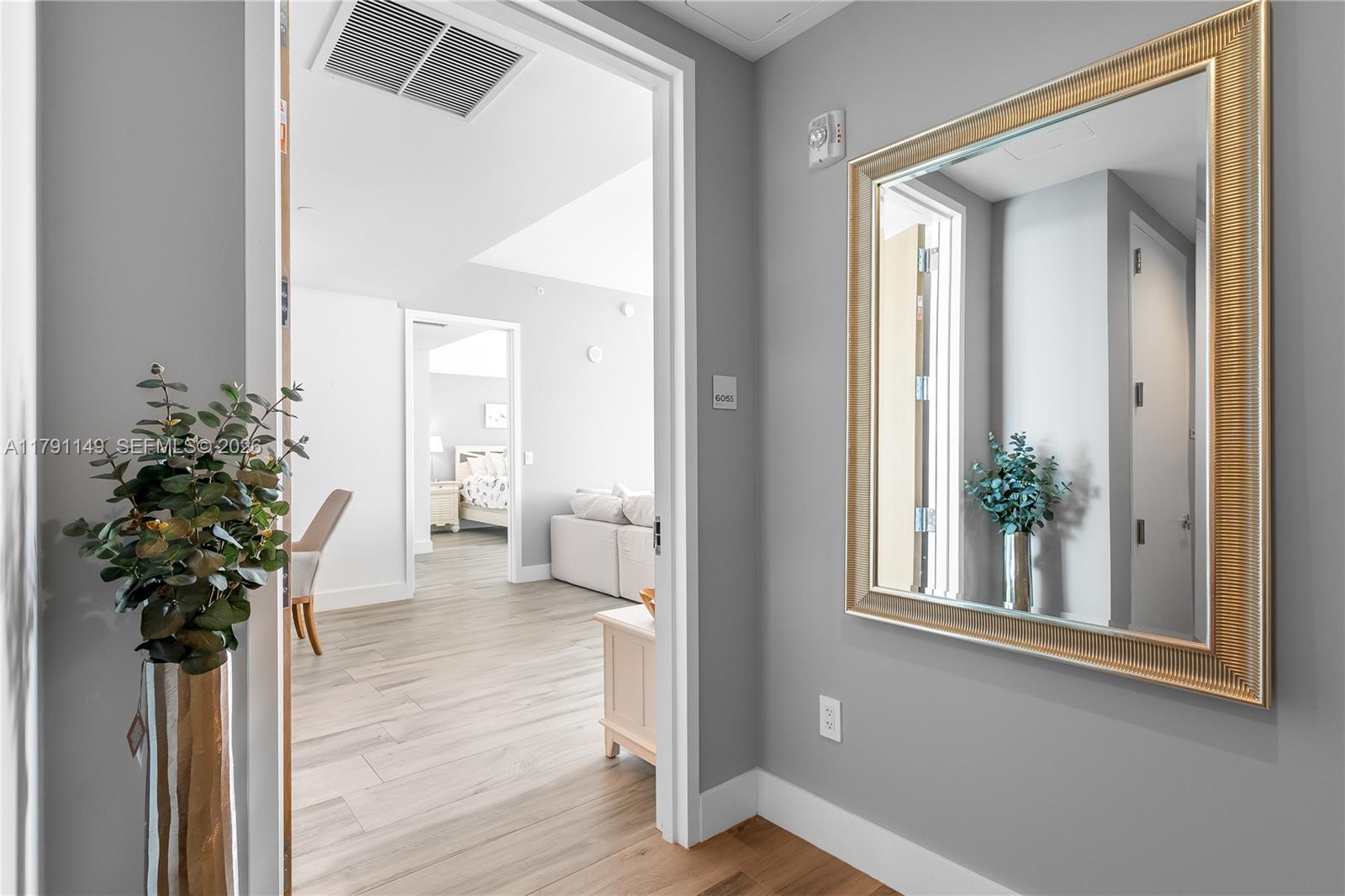 A gray-walled hallway features a gold-framed mirror and a doorway leading to a living area — 10201 Collins Ave # 605, Bal Harbour FL 33154, BAL HARBOUR, FL