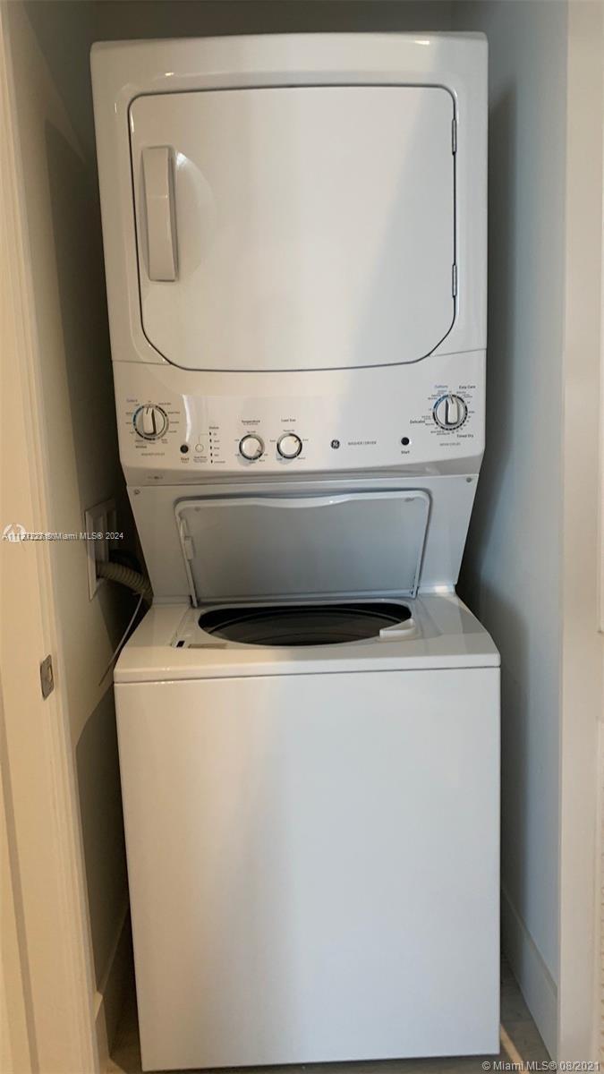 A white stacked washer and dryer unit is installed in a small laundry closet — 4010 S Ocean Dr # R401, Hollywood FL 33019, HOLLYWOOD, FL