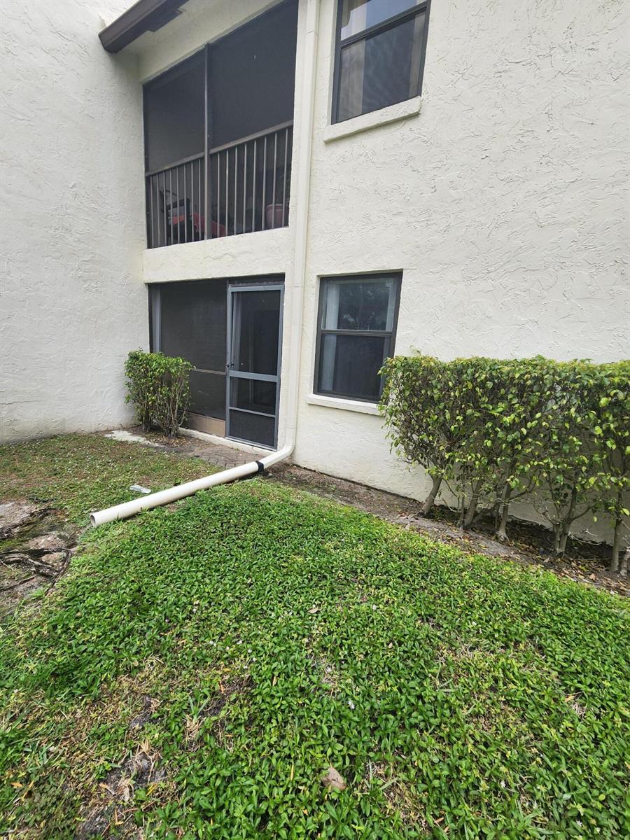 The exterior of a two-story building features a screened balcony, a patio door, and landscaping — 3345 Lucerne Park Drive, FL 33467, FL