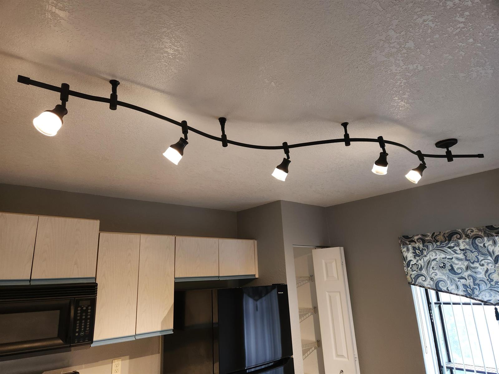 A kitchen features a curved black track lighting system mounted on a textured white ceiling — 3345 Lucerne Park Drive, FL 33467, FL