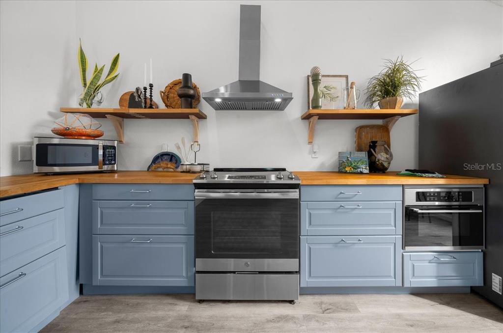 A kitchen features blue cabinets, wood countertops, stainless steel appliances, and open shelving — 2925 N RIVERS EDGE BOULEVARD UNIT 2925, CRYSTAL RIVER, FL