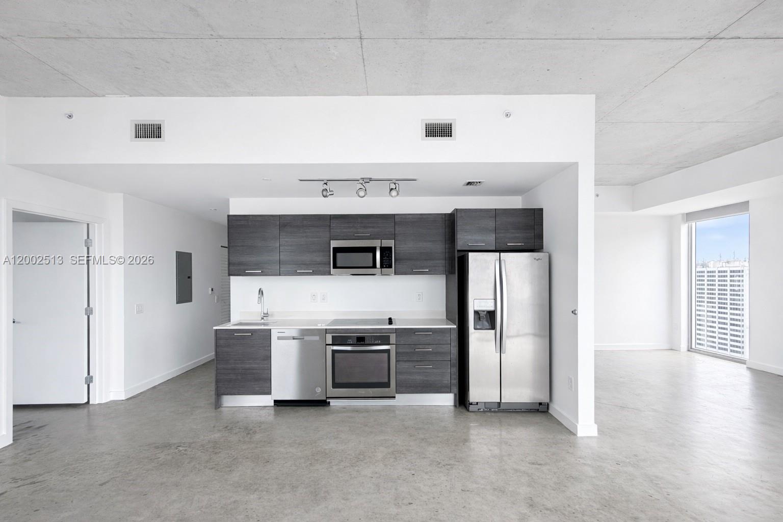 A modern kitchen features dark wood cabinets, stainless steel appliances, and polished concrete floors — 151 SE 1st St # 3001, Miami FL 33131, MIAMI, FL